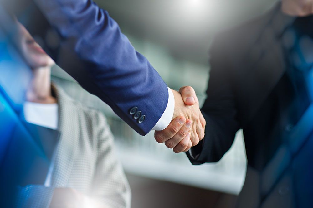 Business handshake between two professionals in suits, symbolizing partnership and agreement in a corporate setting.
