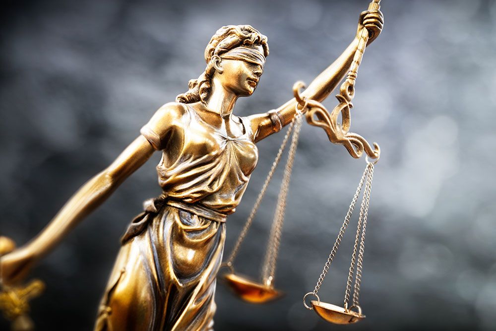 Blindfolded Lady Justice statue holding scales, symbolizing fairness and law.