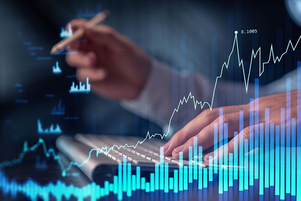 Person analyzing financial charts on screen with hand typing on keyboard, illustrating digital market analysis.