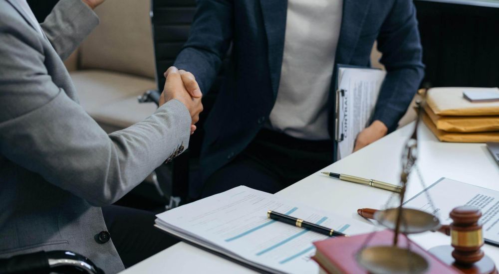a couple of people shaking hands over a desk