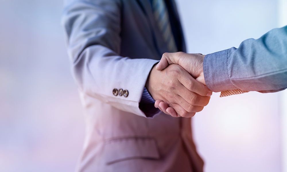 Businessmen in suits shaking hands, symbolizing partnership and successful professional agreement.