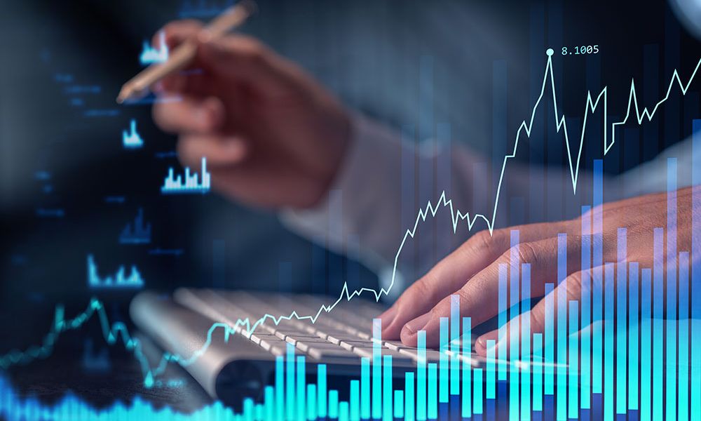 Person analyzing financial charts on screen with hand typing on keyboard, illustrating digital market analysis.