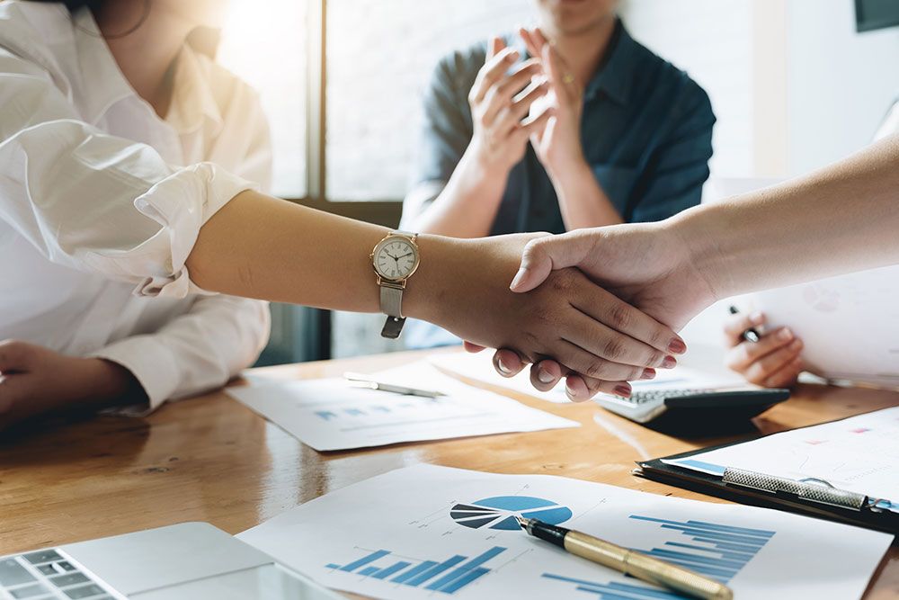 Business meeting handshake with charts on table, teamwork concept.