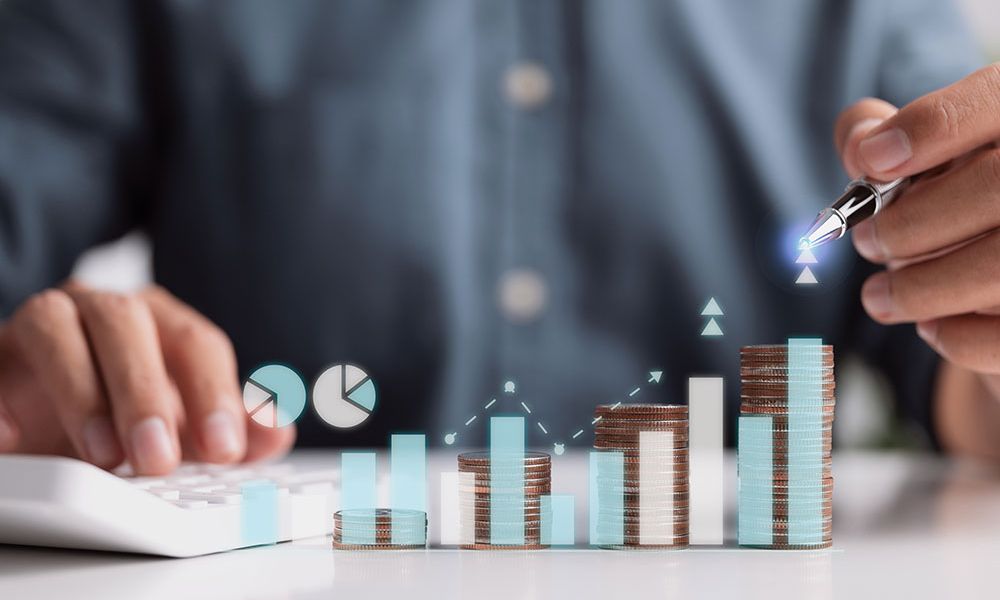 Person analyzing financial growth with calculator, money stacks, and charts, highlighting business investment insights.