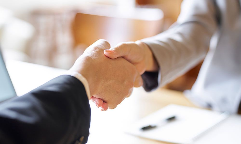 Business professionals shaking hands in agreement at a meeting, symbolizing partnership and collaboration.