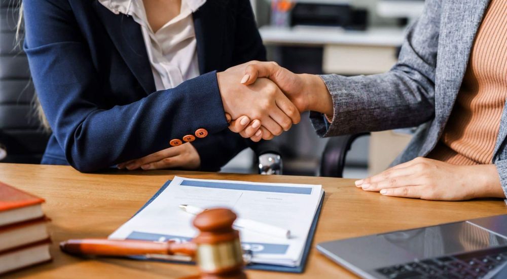 a couple of people shaking hands over a desk