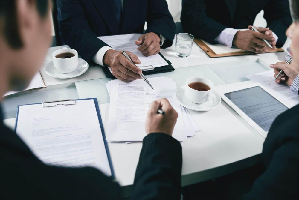 a group of people sitting around a table with papers