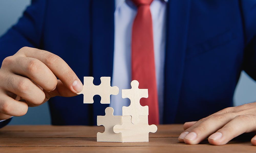 Businessman in suit solving puzzle, symbolizing strategy and problem-solving.