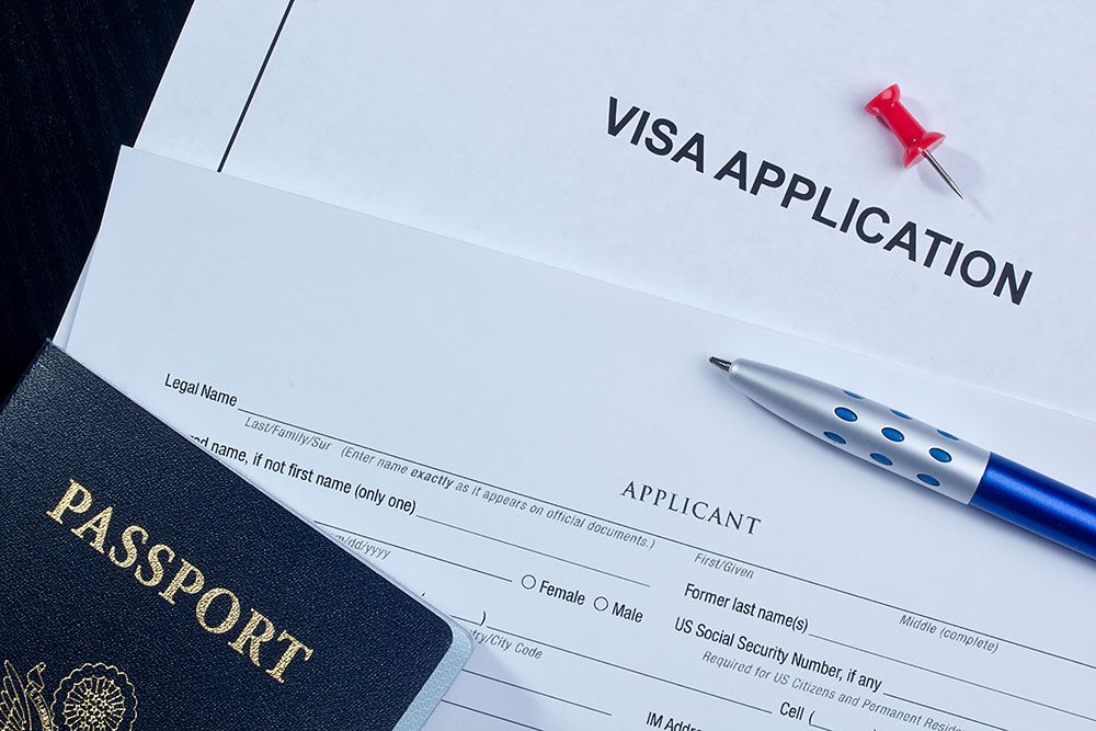 Visa application form with passport, pen, and thumbtack. Travel documents for visa processing.