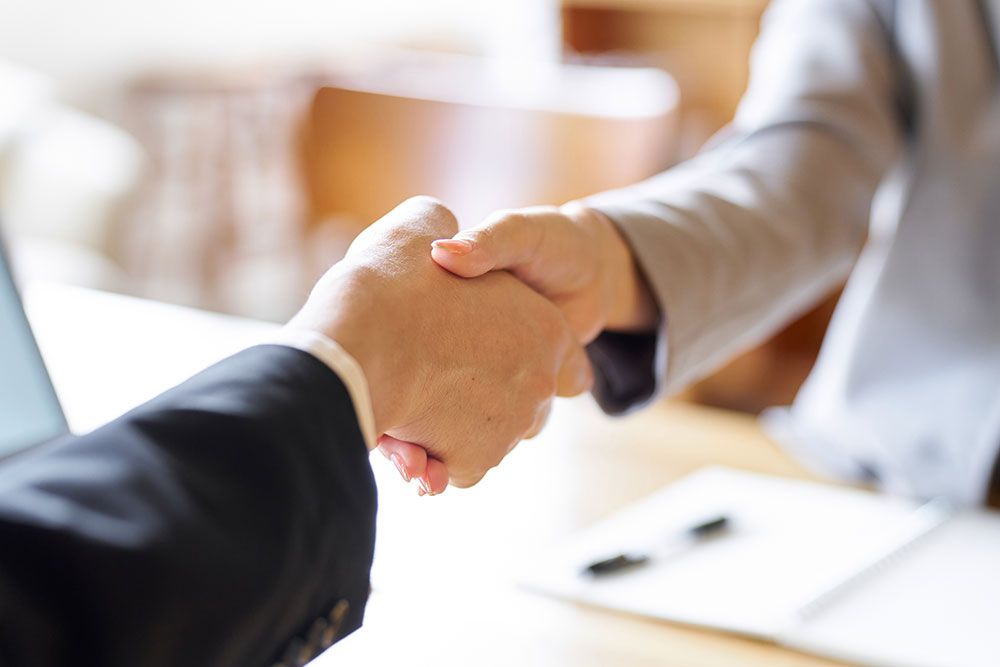 Business professionals shaking hands in agreement at a meeting, symbolizing partnership and collaboration.