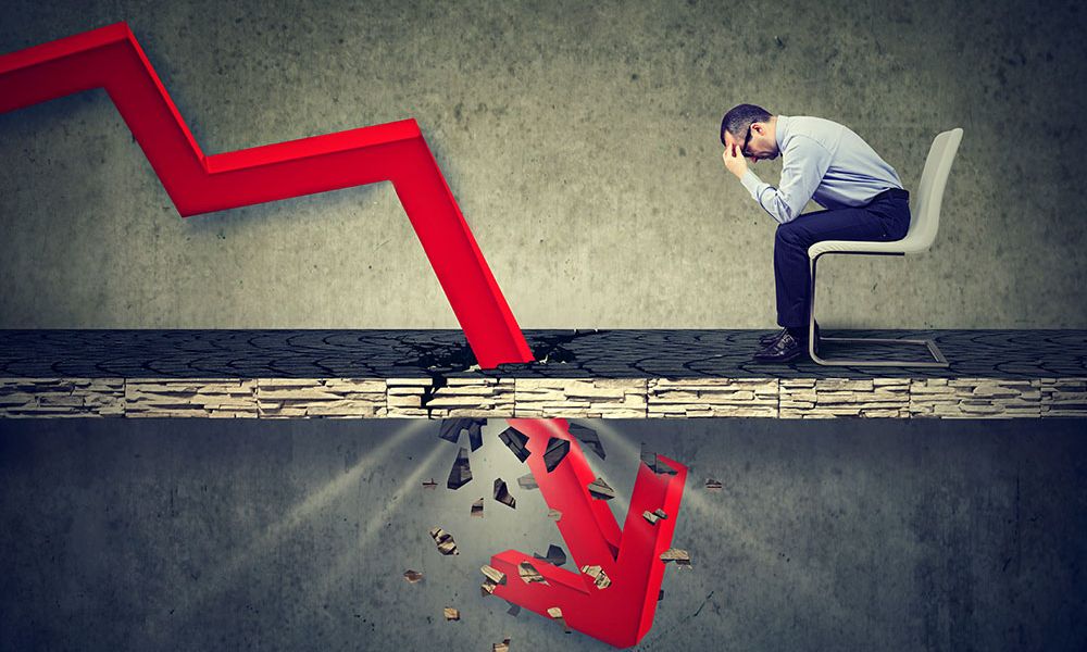 Businessman stressed by declining financial graph breaking the surface.
