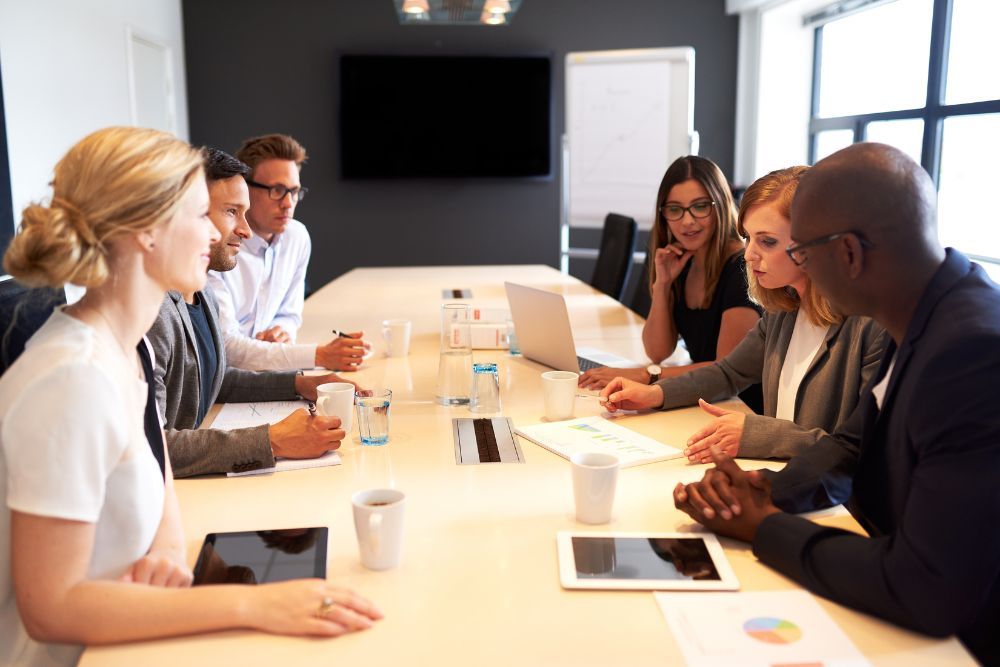 Business team in a meeting discussing strategy with documents and laptops in a modern conference room.