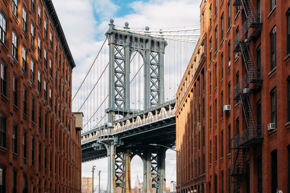 Iconic bridge framed by red brick buildings under a blue sky. Urban cityscape with architectural contrast.