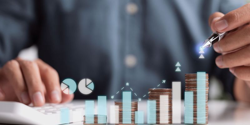 Person analyzing financial growth with calculator, money stacks, and charts, highlighting business investment insights.