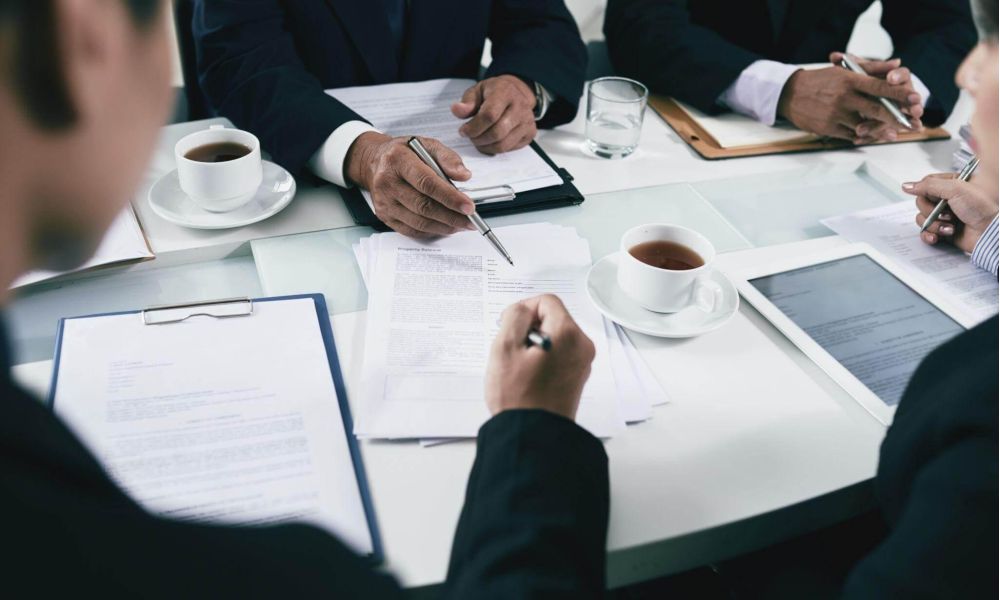 a group of people sitting around a table with papers