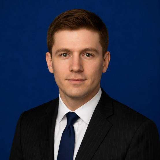 Smiling professional in a suit with a blurred office background, representing business leadership or corporate success.