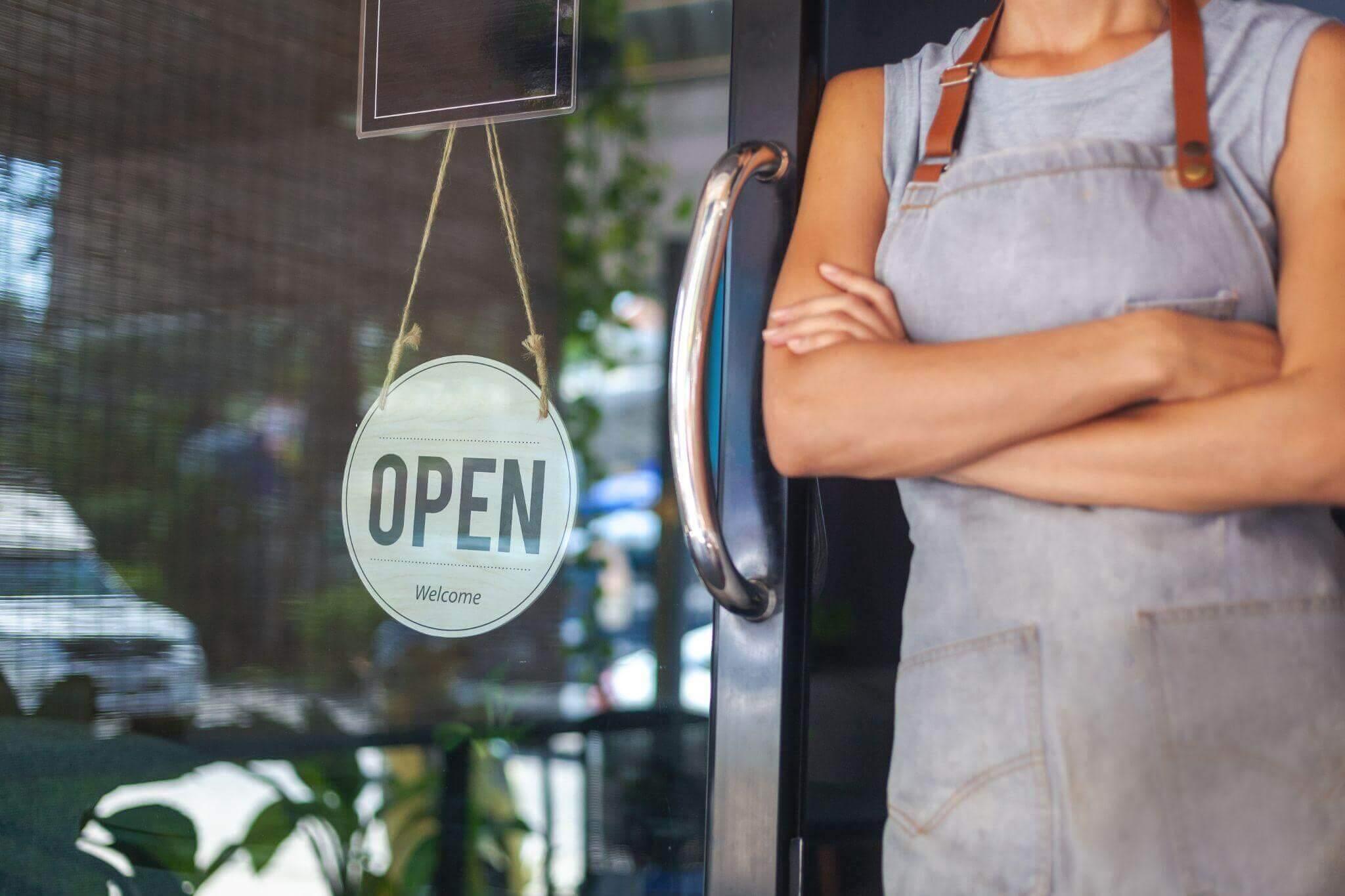 Woman at restaurant door with open sign
