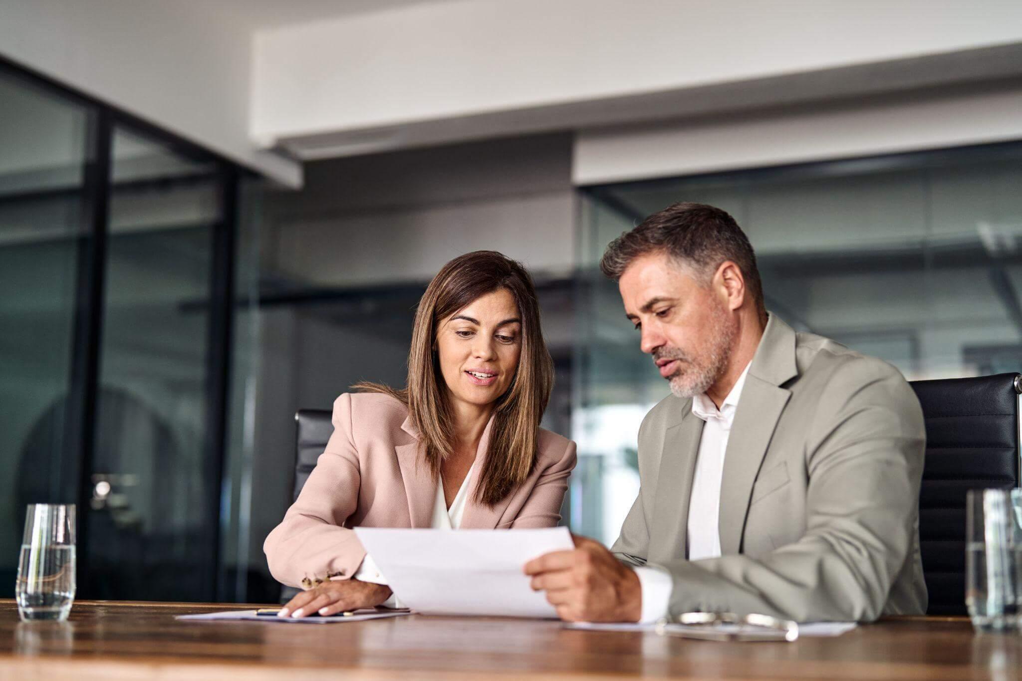 a man and woman sitting at a table looking at a piece of paper