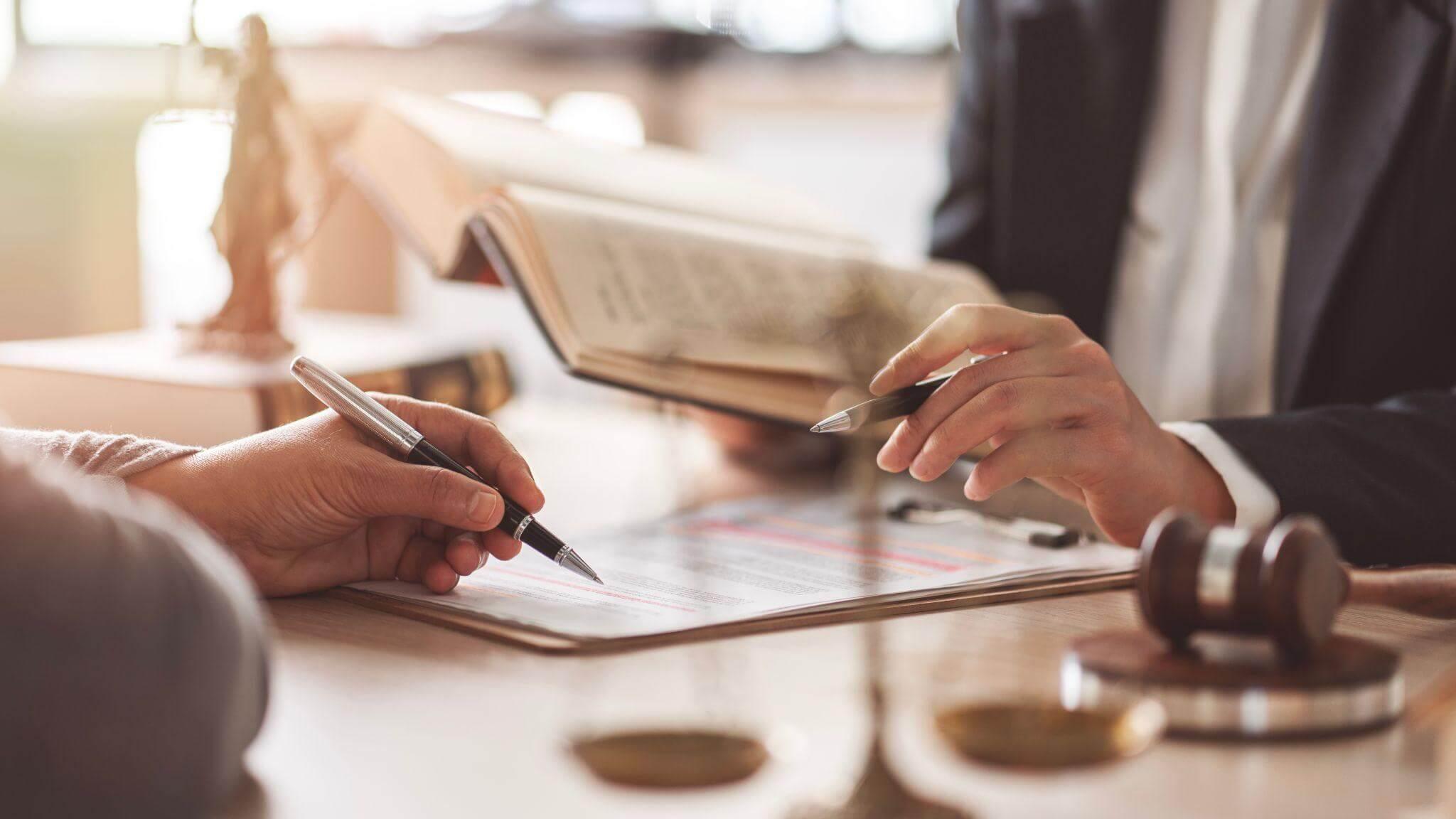 two people sitting at a table with a book and pen