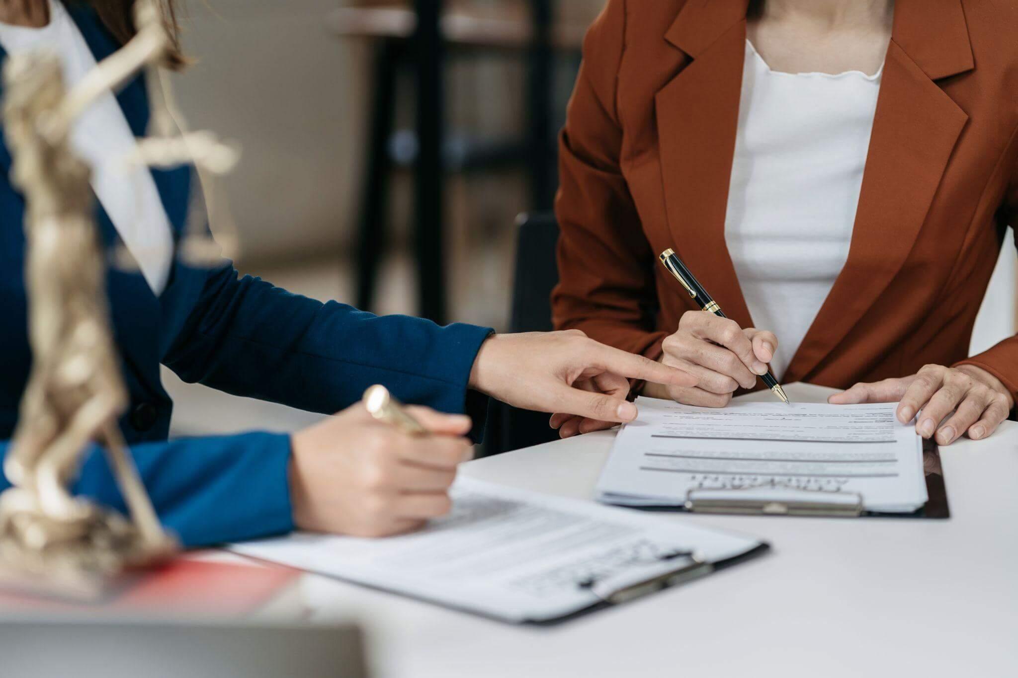 two women sitting at a table signing papers