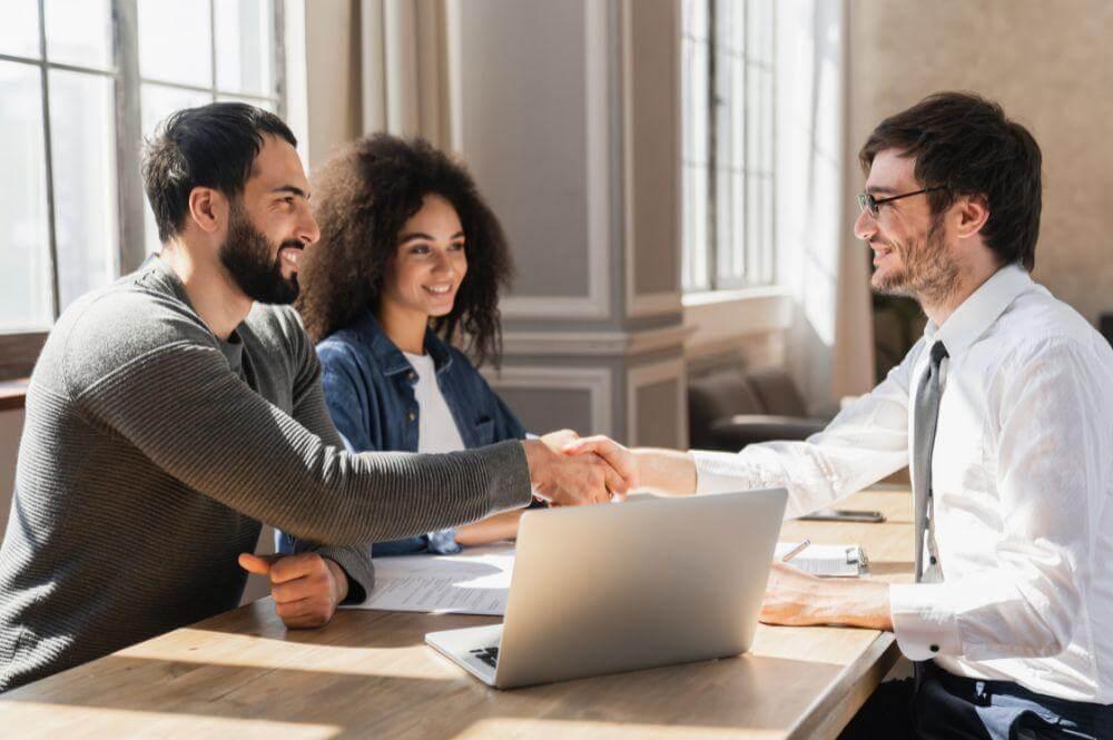 Business professionals shaking hands over a laptop finalizing a commercial